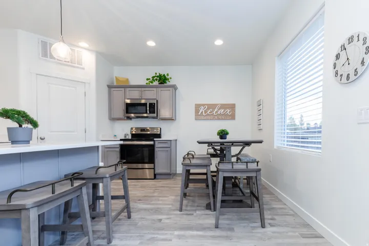 Contemporary kitchen featuring light gray cabinetry, stainless steel appliances, and wood-finish flooring