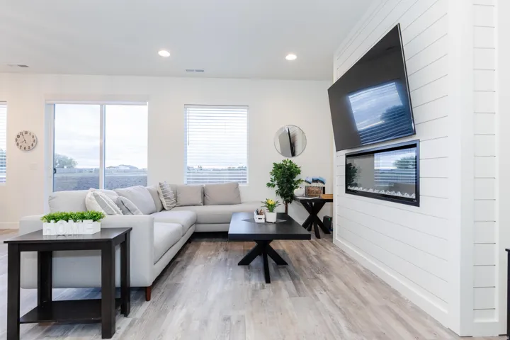 Living area featuring white shiplap accent wall with built-in electric fireplace, wood-finish flooring, recessed lighting, and sliding glass door