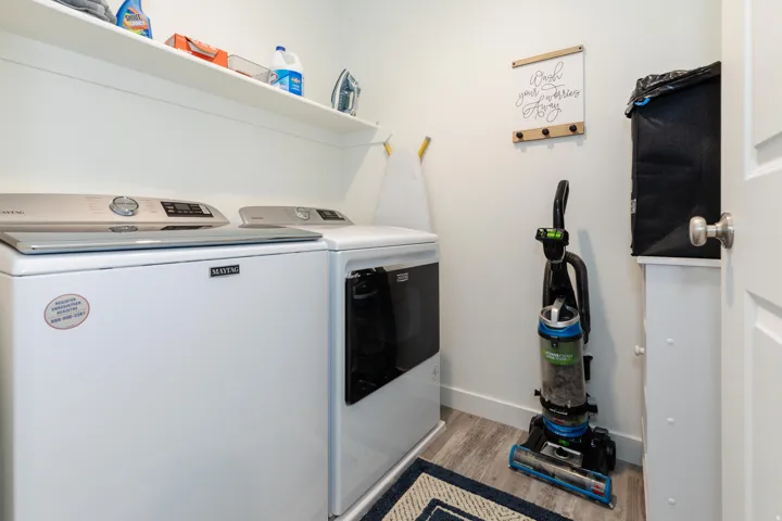 Dedicated laundry area featuring a built-in shelf, light wood-finish flooring, and crisp white walls