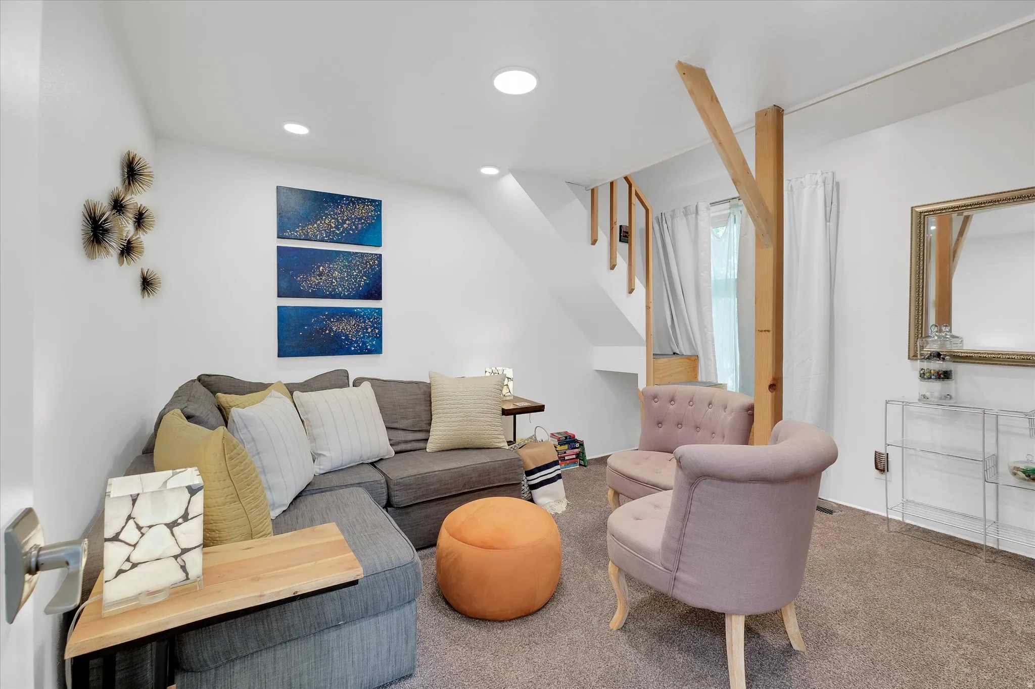 Carpeted living space featuring recessed lighting, white walls, and an exposed wooden support beam
