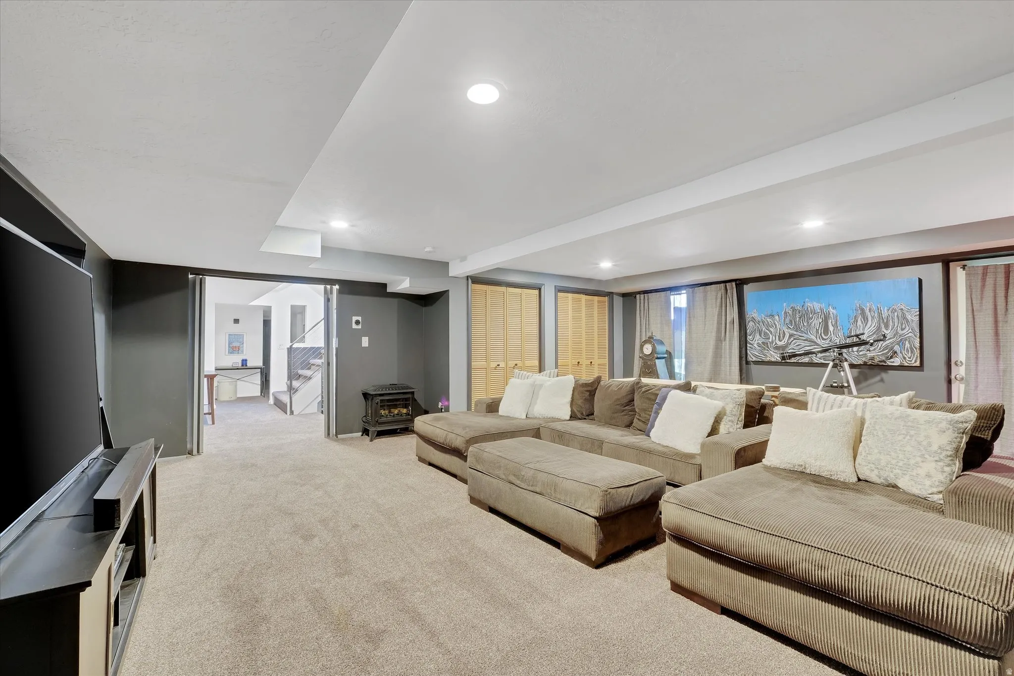Carpeted recreation room with recessed lighting, dark gray walls, white trim, and bi-fold closet doors