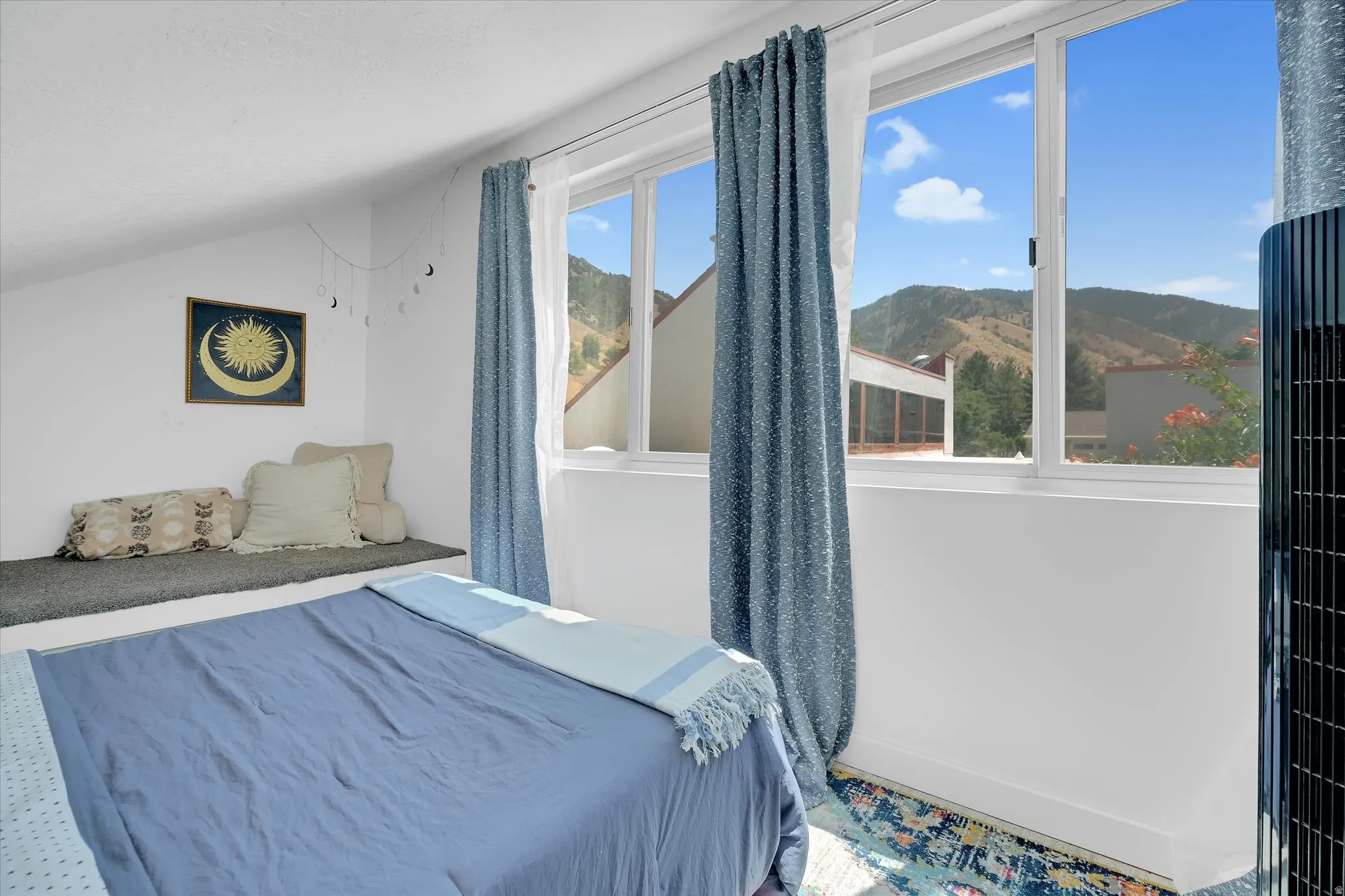 Room featuring multiple windows, a mountain backdrop, an angled ceiling, a built-in bench, and wood-finish flooring