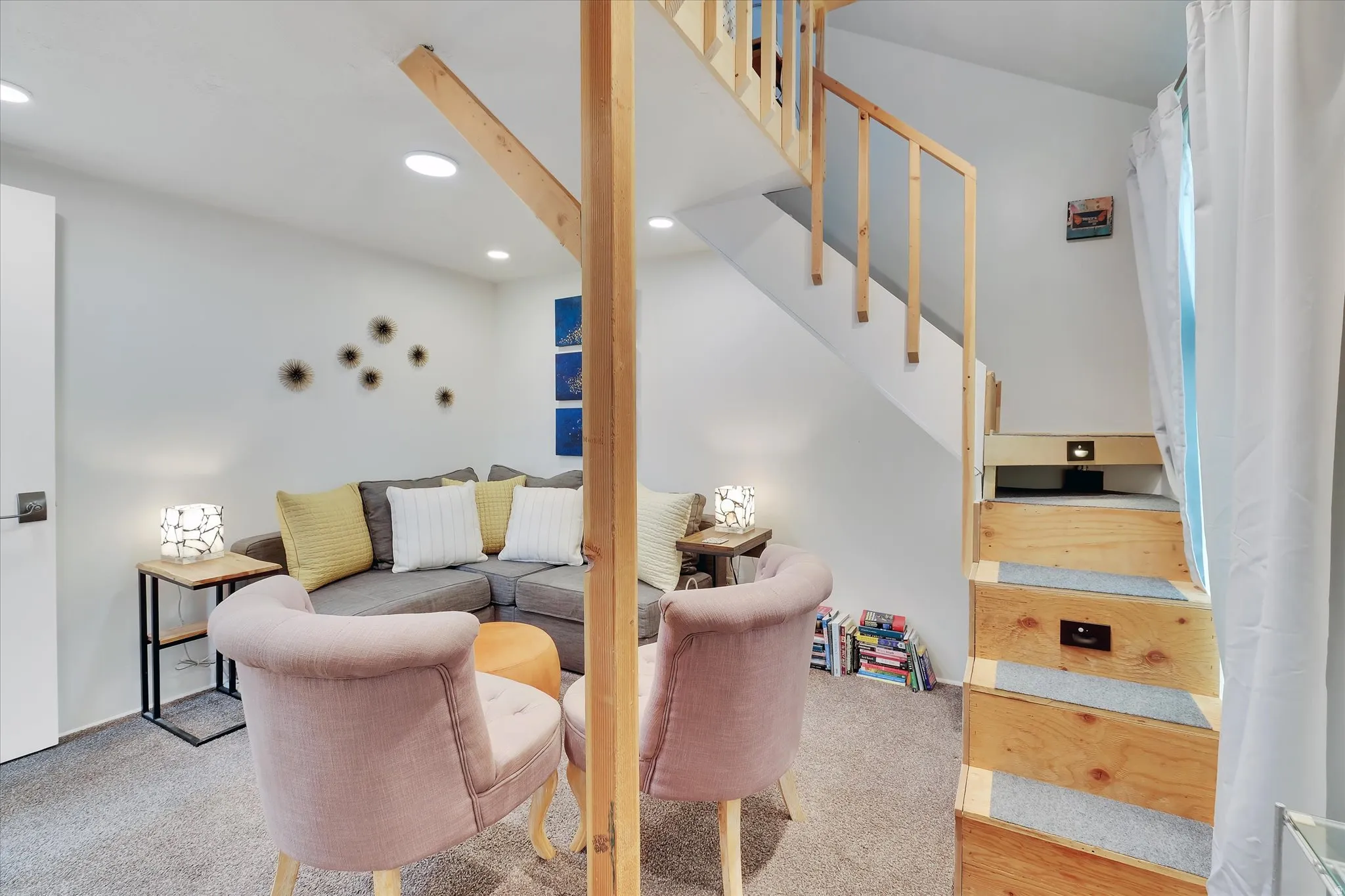 Carpeted living area featuring recessed lighting, a built-in wooden staircase with integrated lighting, and a white interior door with dark hardware
