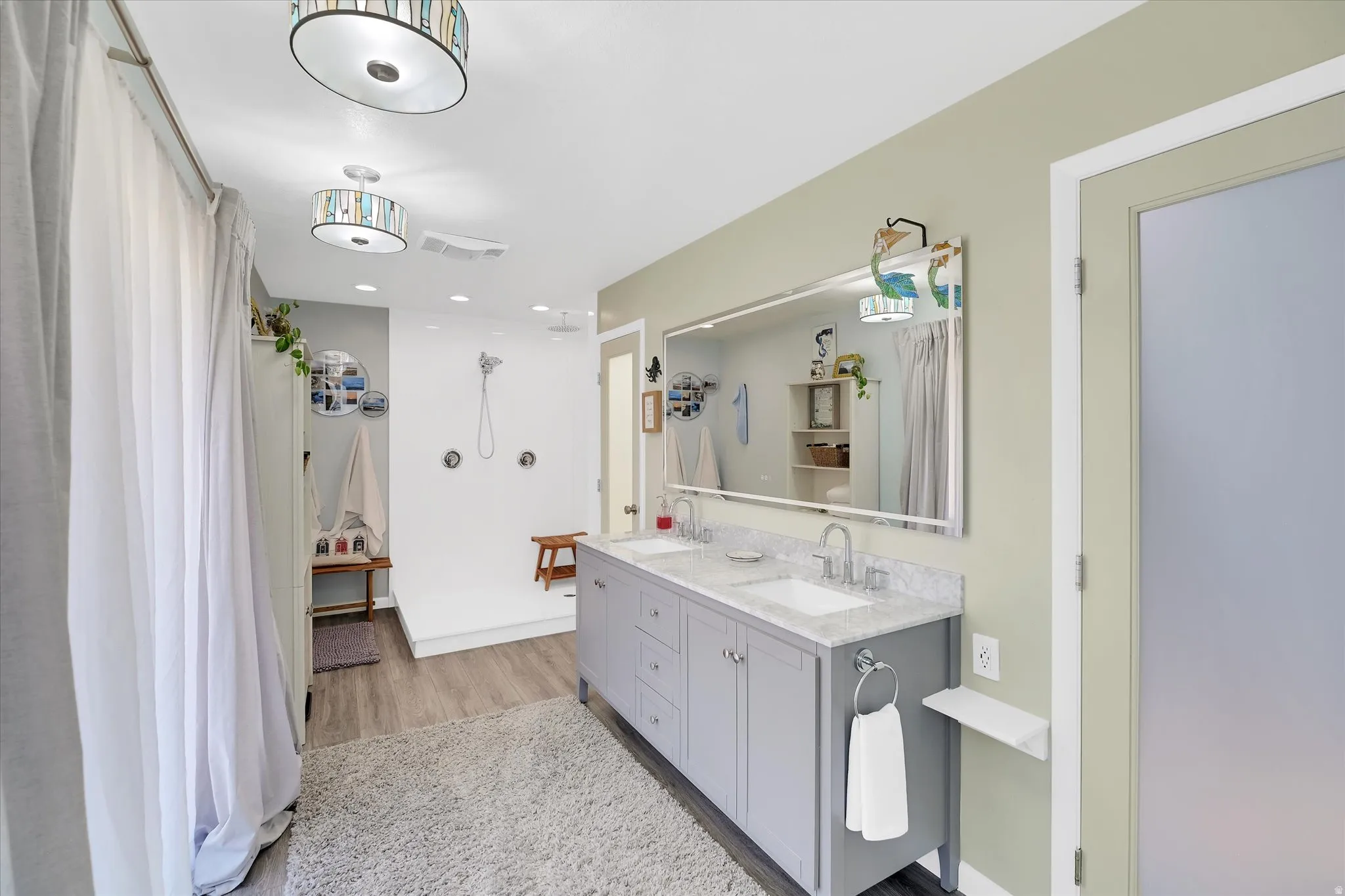 Bathroom featuring a dual vanity with light gray cabinetry, white rectangular sinks, and a light-colored speckled countertop