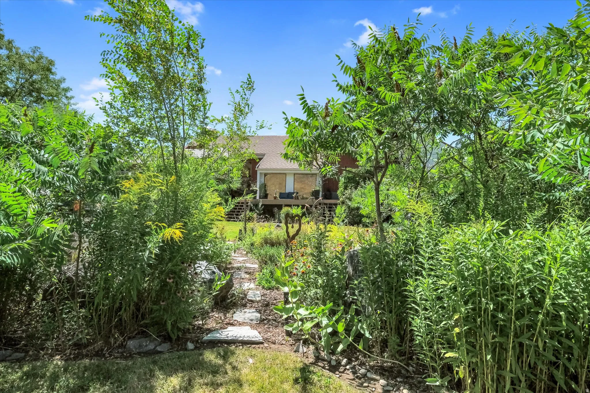 Expansive backyard path featuring natural stone pavers surrounded by mature plantings and diverse foliage