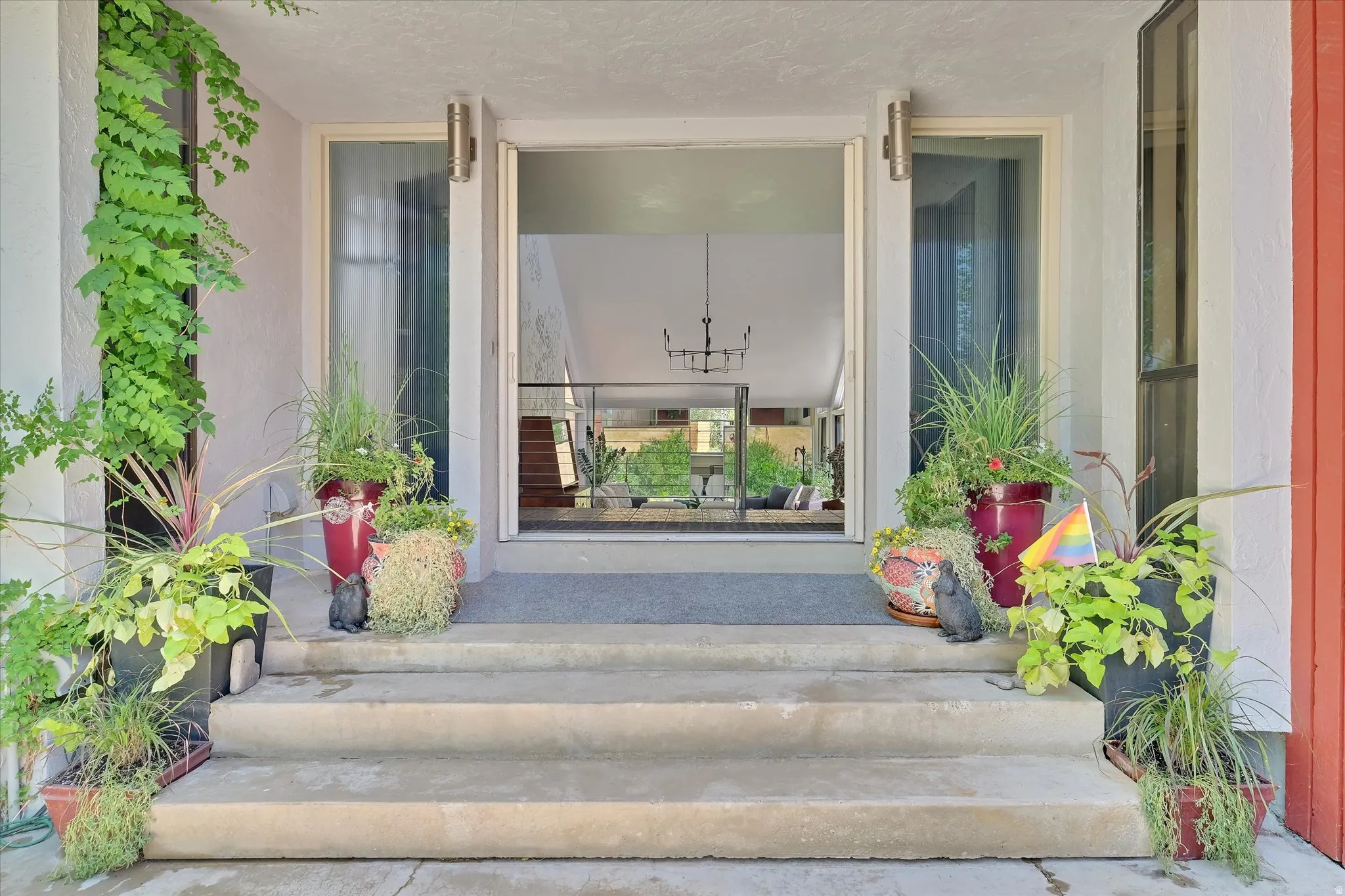Concrete entry steps leading to a recessed entryway with frosted glass sidelights and an open doorway
