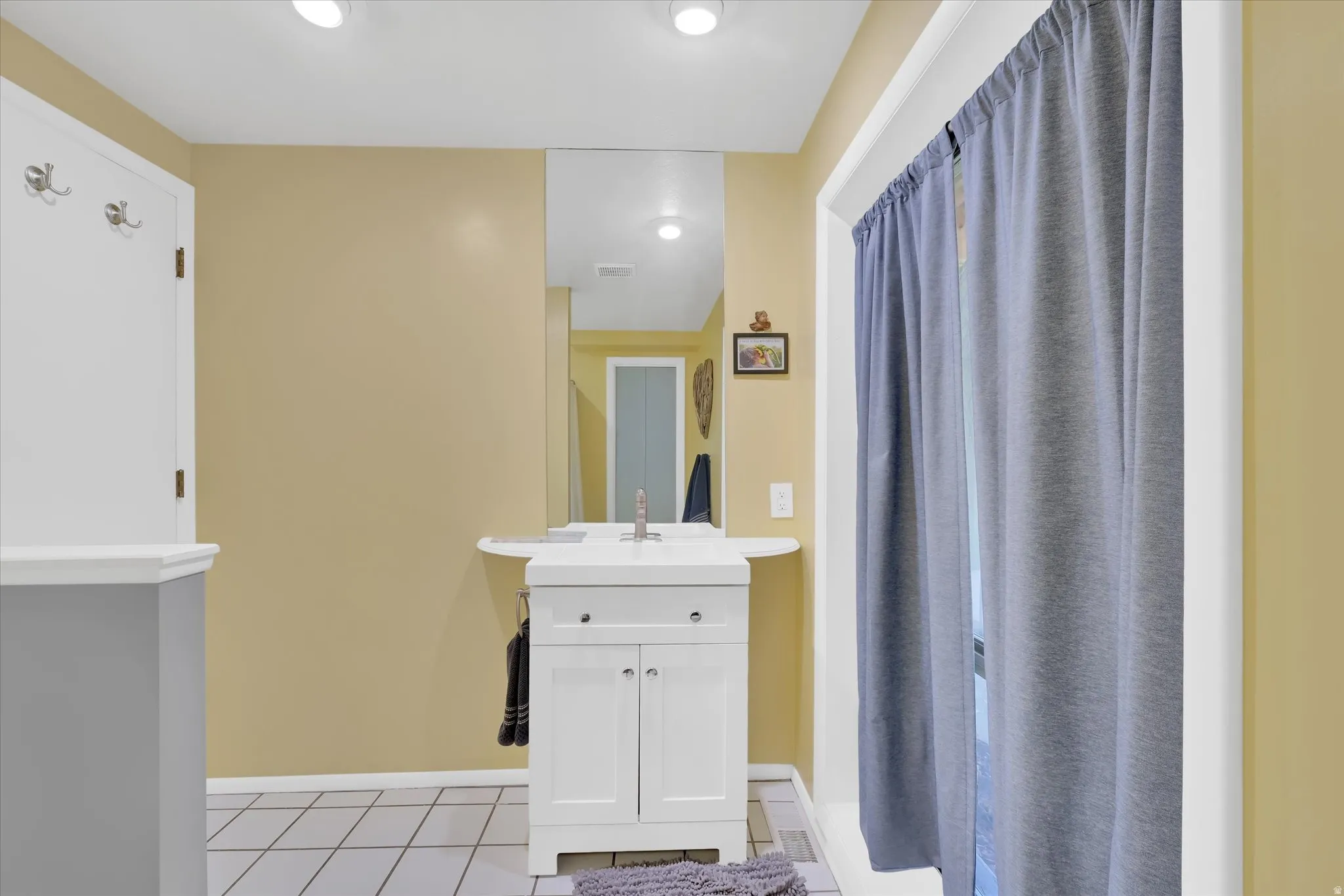 Bathroom featuring a white vanity with integrated sink, chrome faucet, and mirrored wall
