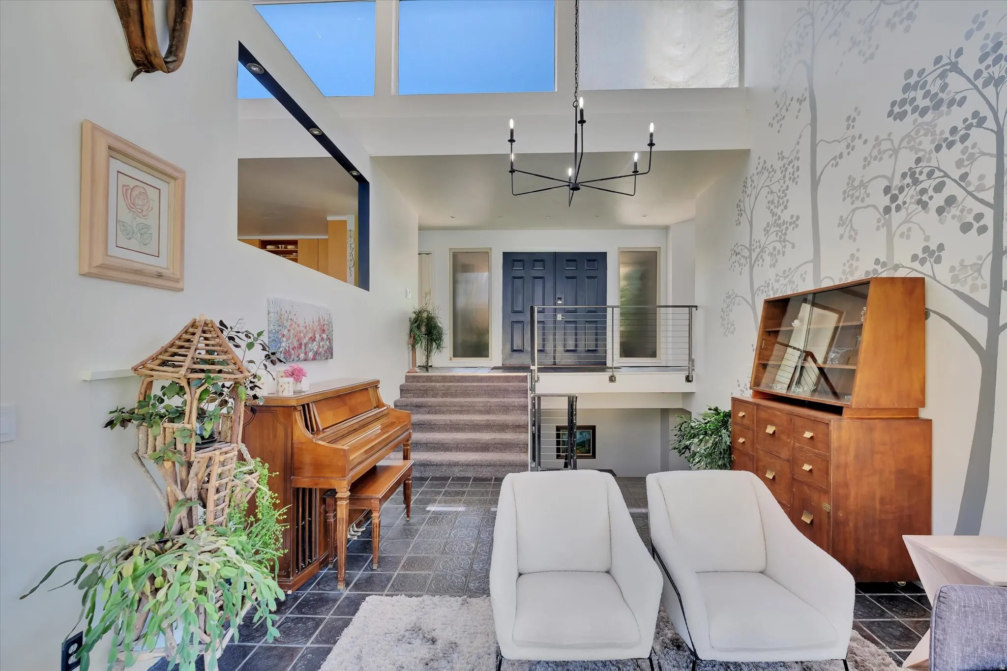 Foyer featuring slate tile flooring, a two-story ceiling with skylights, and a contemporary chandelier