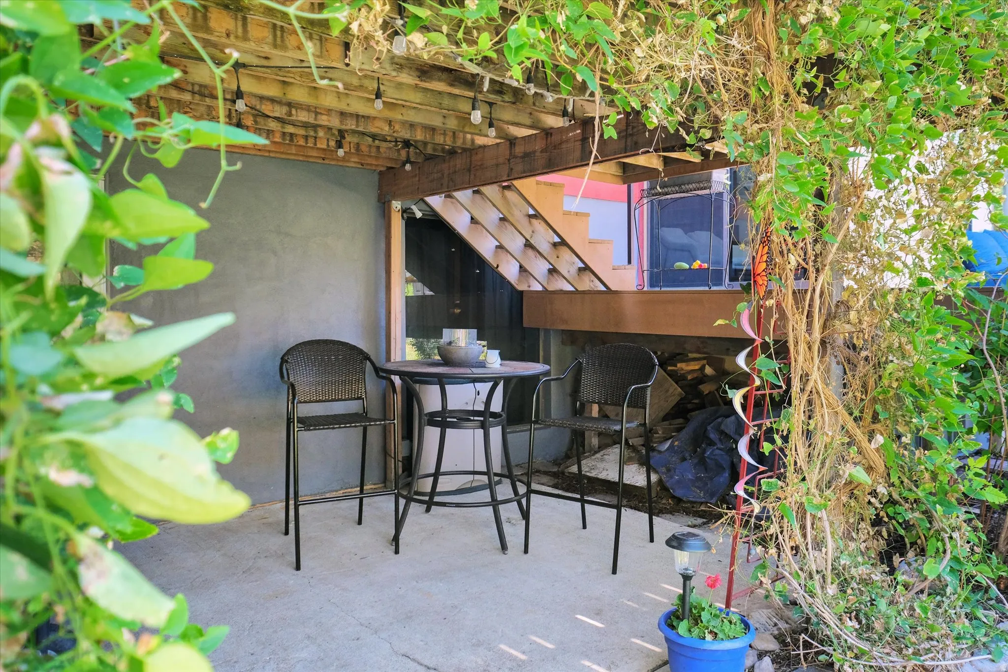 Outdoor patio area with a concrete slab, overhead wood pergola, and string lighting