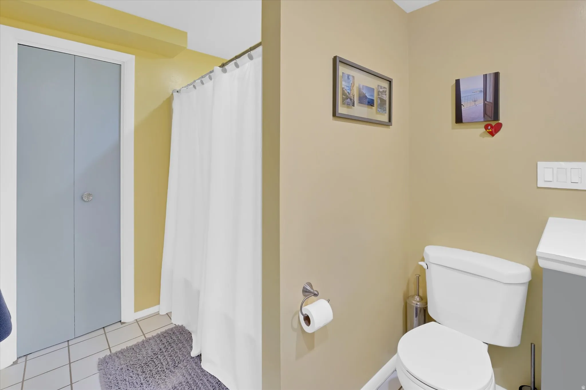 Bathroom featuring a white toilet, tile flooring, and a shower with a white curtain