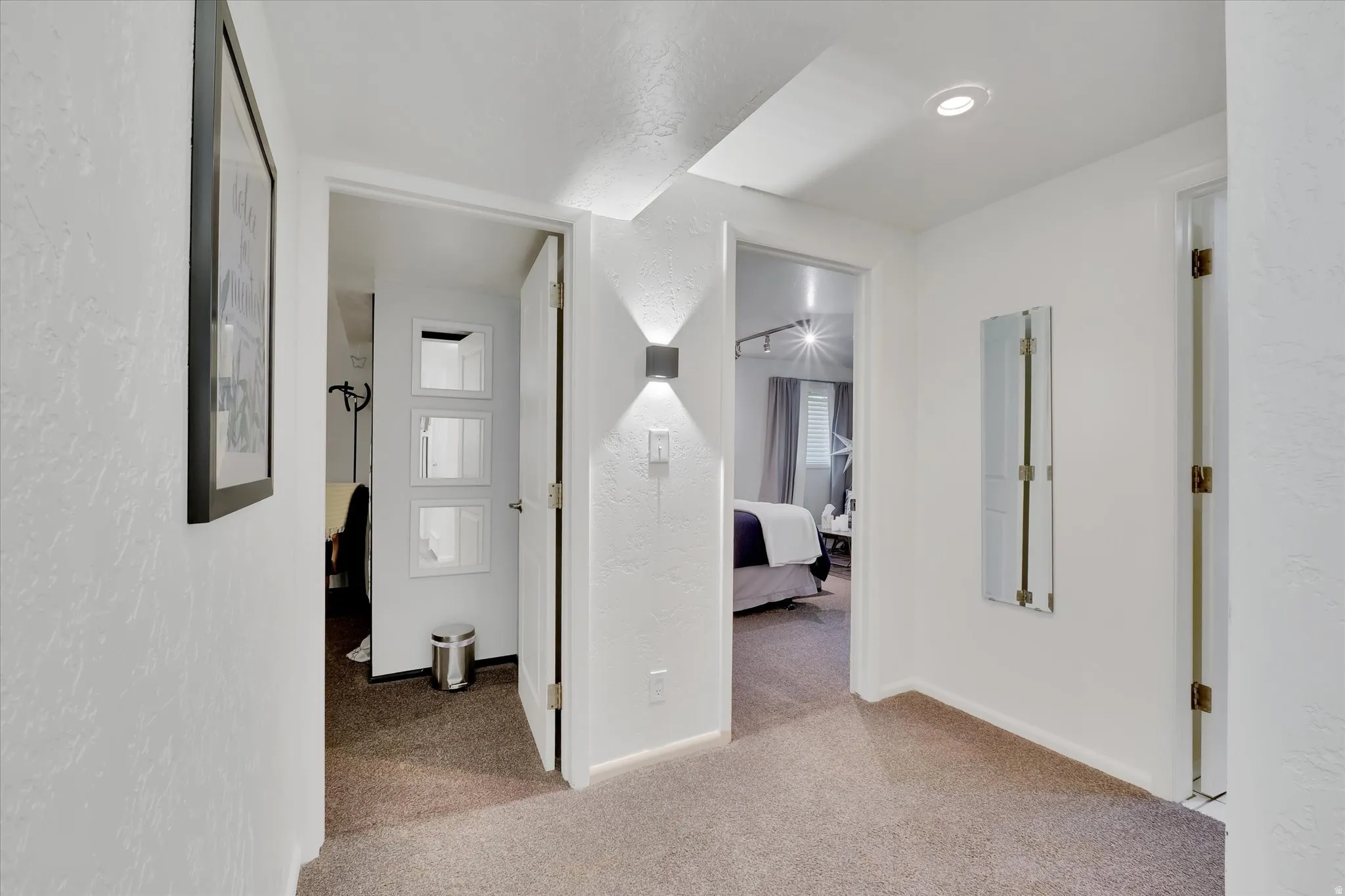Carpeted hallway with white walls and overhead recessed lighting