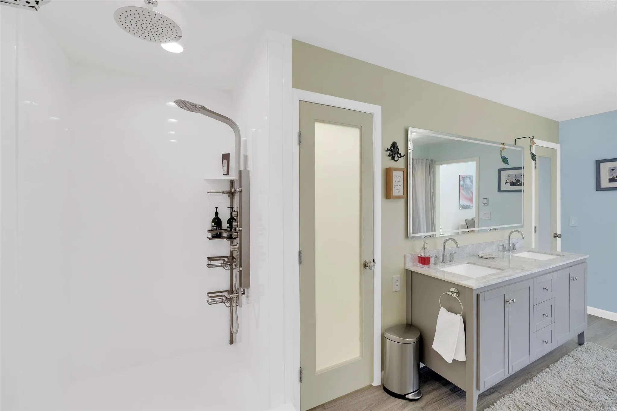 Bathroom featuring a dual vanity with undermount sinks and a stone countertop, a large framed mirror, and a walk-in shower with a rain shower head and a multi-function shower panel