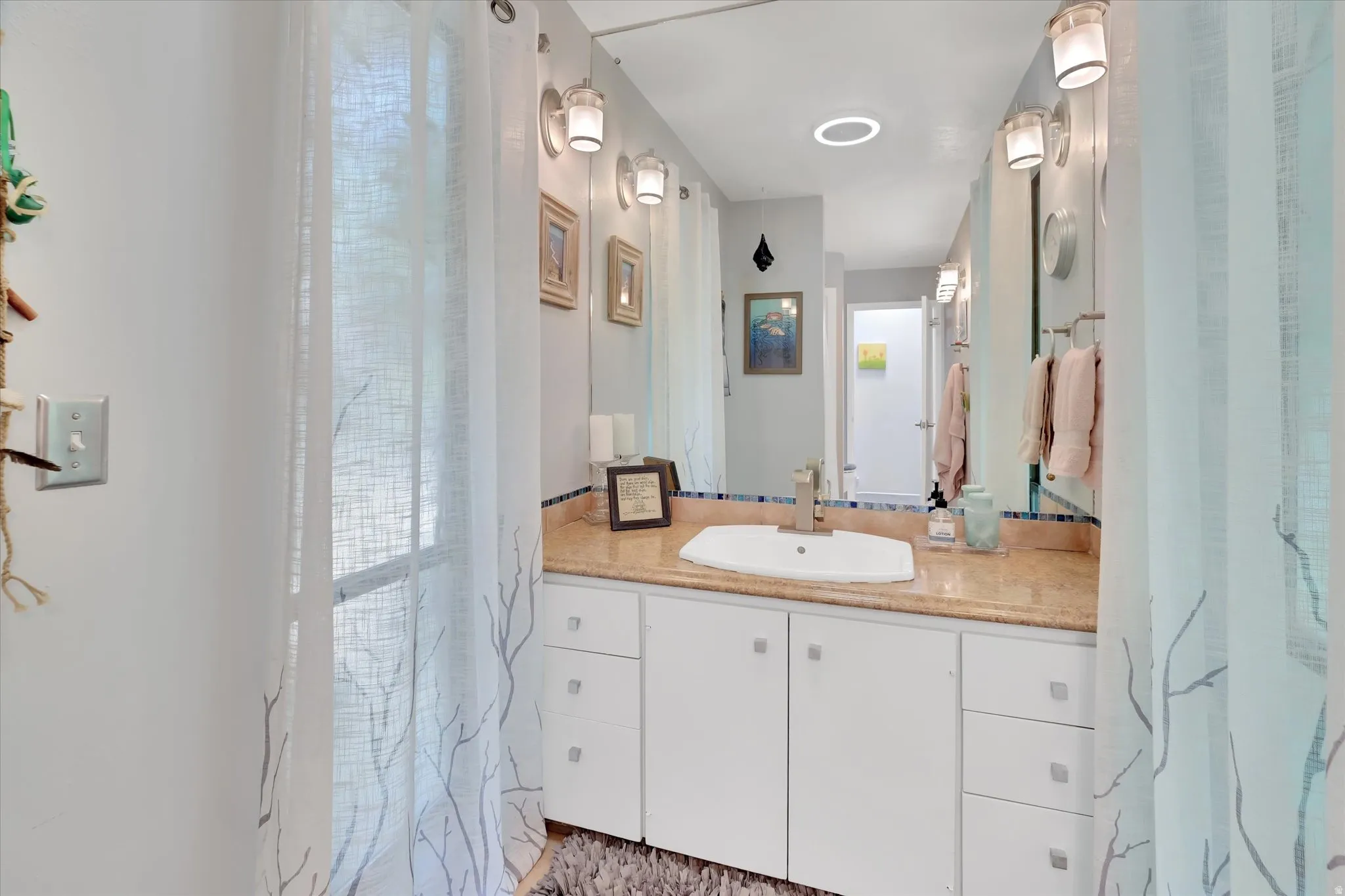 Vanity featuring a rectangular basin, stone countertop, brushed nickel faucet, and a large wall-mounted mirror