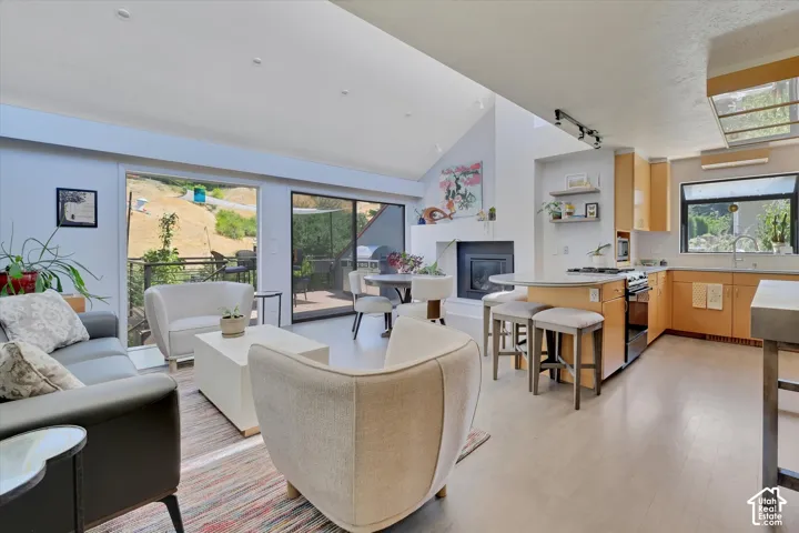 Open-concept living space featuring high vaulted ceilings, light-tone wood-finish flooring, and an integrated kitchen