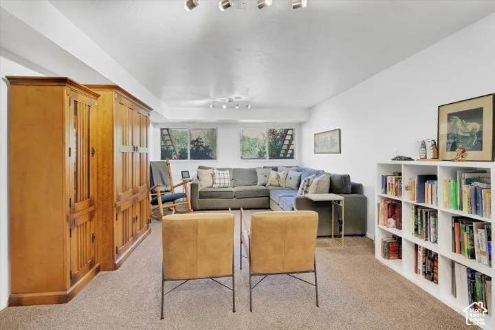 Spacious room featuring carpeted flooring, track lighting, and two egress windows