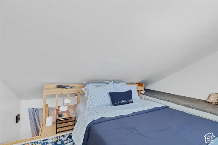 Loft sleeping area featuring a built-in wooden bed frame, sloped ceiling, and an integrated carpeted bench