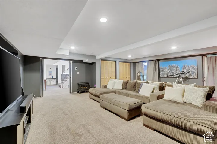 Carpeted recreation room with recessed lighting, dark gray walls, white trim, and bi-fold closet doors