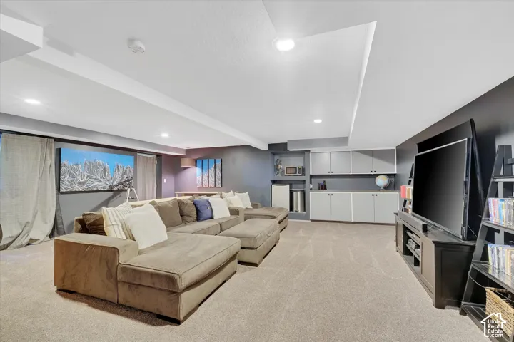 Carpeted recreation room featuring recessed lighting, a built-in entertainment center, and integrated cabinetry with shelving