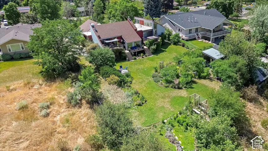 Tiered landscaping with expansive green lawn, mature trees, and established garden beds