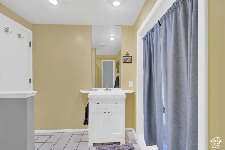 Bathroom featuring a white vanity with integrated sink, chrome faucet, and mirrored wall
