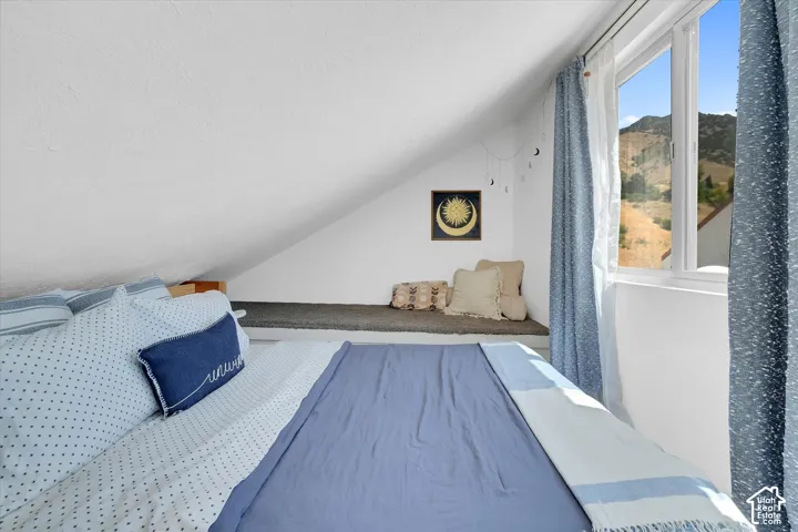 Sloped ceiling room featuring a large window, a built-in window seat, and mountain scenery