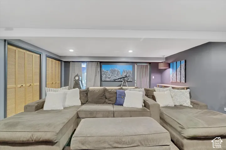 Recessed lighting illuminates this space featuring louvered bi-fold closet doors, a built-in wall shelf, and curtained windows