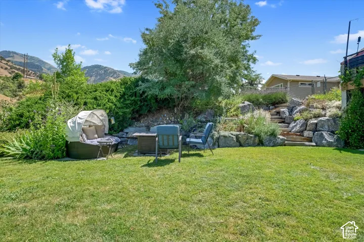 Expansive grassy yard with tiered rock landscaping and natural wood steps