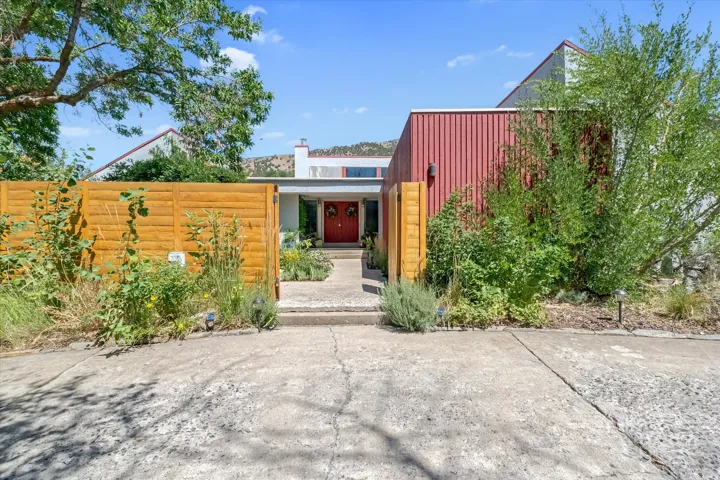 Contemporary exterior featuring a red corrugated metal accent wall, a red front door, and a horizontal wood fence