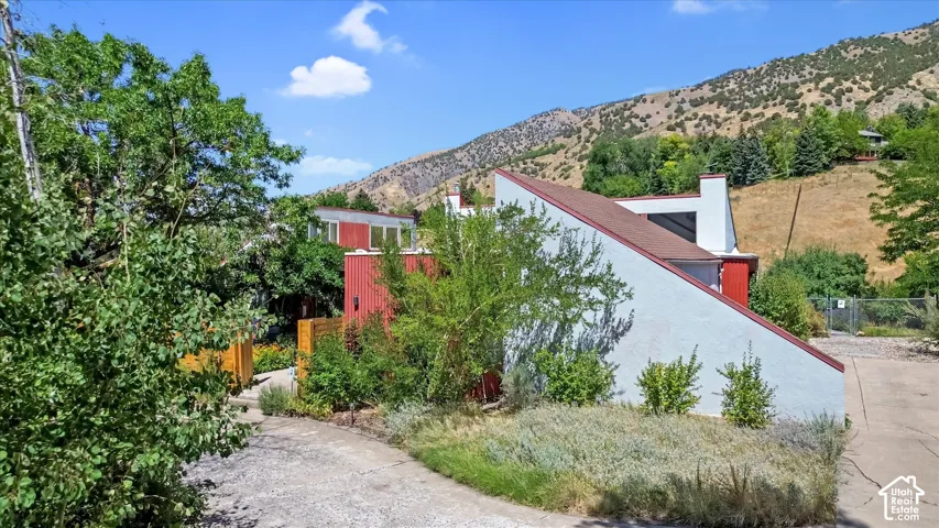Modern architectural design featuring a red and white exterior, a sloped roofline, a visible chimney, and mature landscaping