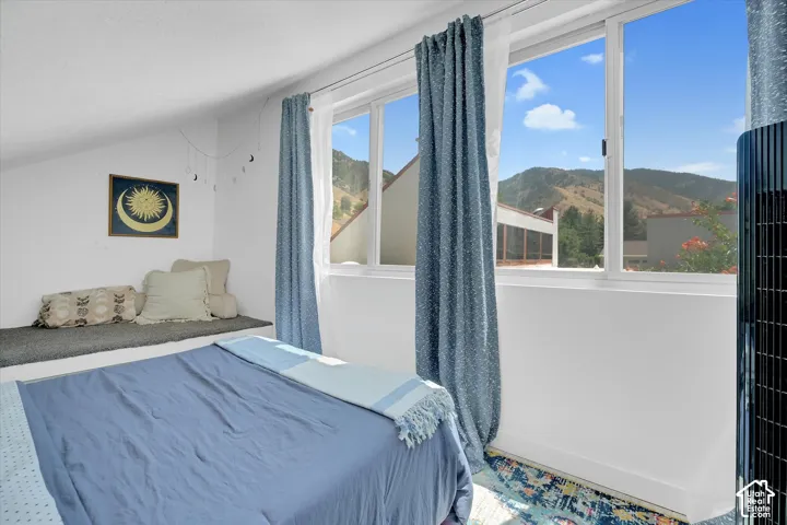 Room featuring multiple windows, a mountain backdrop, an angled ceiling, a built-in bench, and wood-finish flooring