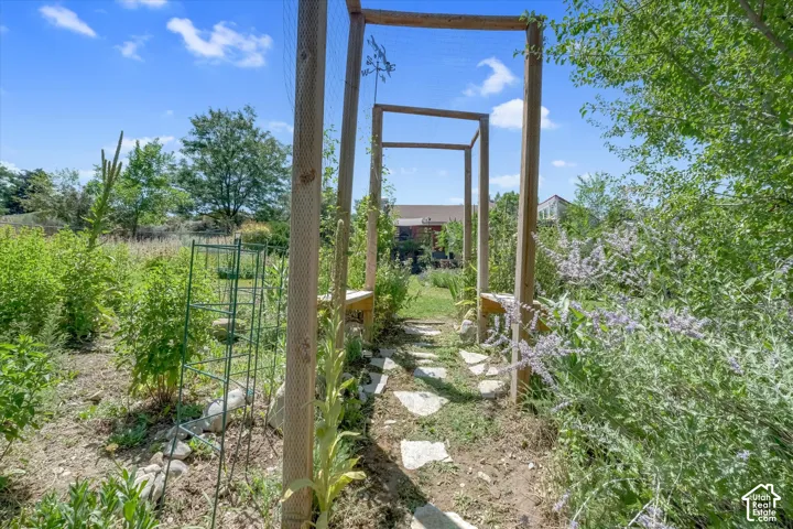 Landscaped garden path featuring stone pavers, natural wood arbor, and established perennial plantings
