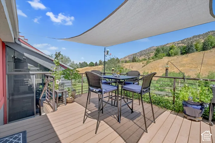 Expansive outdoor deck featuring wood-finish flooring, a white sunshade, and metal railings