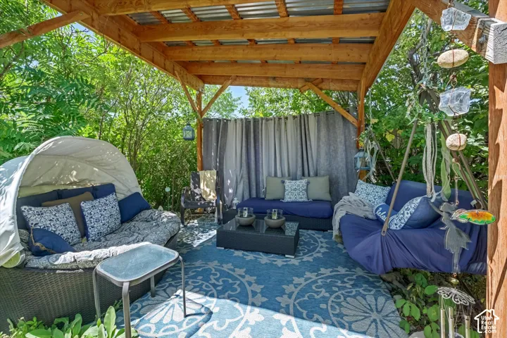 Outdoor wooden pergola featuring a corrugated metal roof, privacy curtains, and a patterned area rug