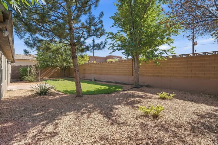 Expansive backyard featuring a central lawn area, mature trees, and gravel landscaping