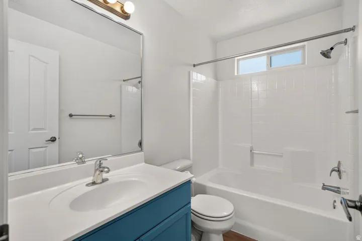 Bathroom featuring a white bathtub with subway tile surround, an overhead transom window, and a single vanity with a blue cabinet