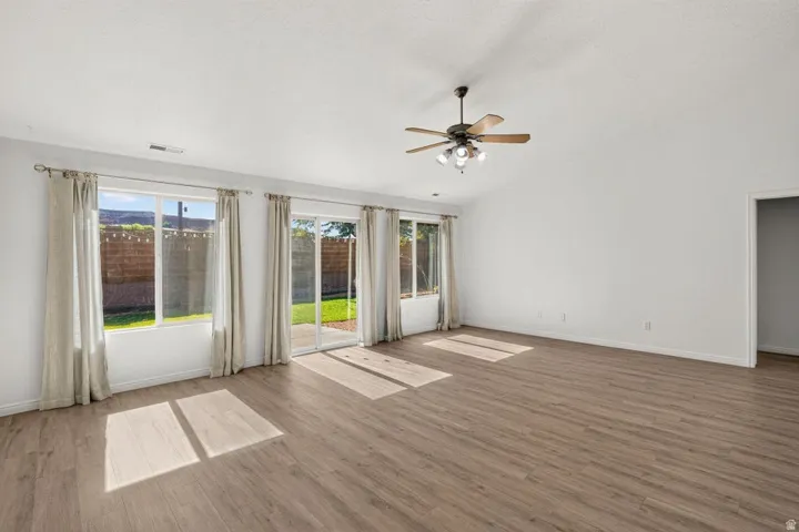 Expansive interior with wood-finish flooring, vaulted ceilings, and a ceiling fan with integrated lighting
