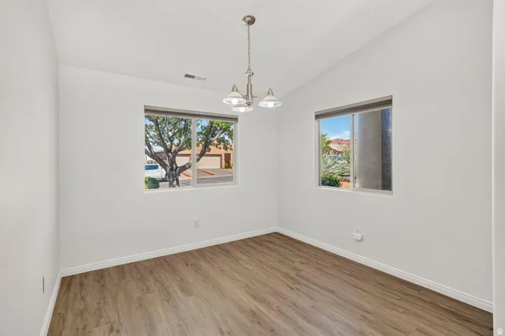 Interior room featuring wood-finish flooring, white walls, and a vaulted ceiling