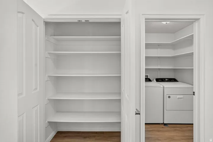 Utility closet featuring wood-finish flooring, white shelving, and a white interior door