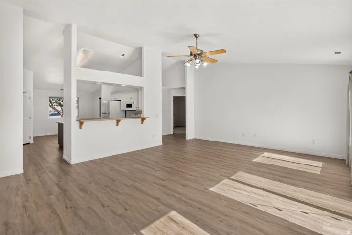 Spacious interior featuring wood-finish flooring, vaulted ceilings, and a pass-through opening to the kitchen