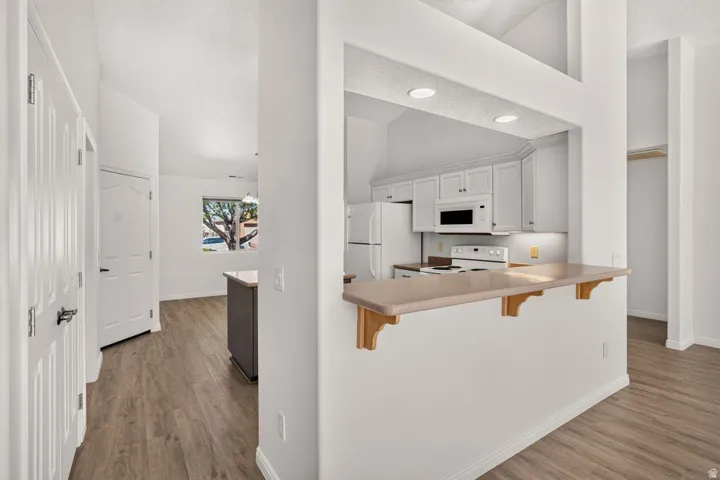 Open-concept kitchen featuring white cabinetry, integrated appliances, and a breakfast bar