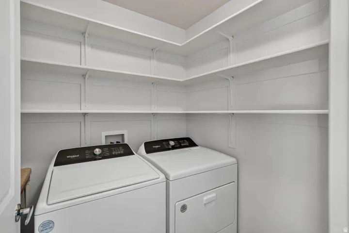 Dedicated laundry area featuring a washer and dryer, white shelving, and white walls