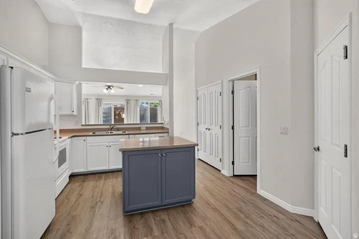 Kitchen featuring a central island with storage, white cabinetry, wood-finish flooring, and vaulted ceilings