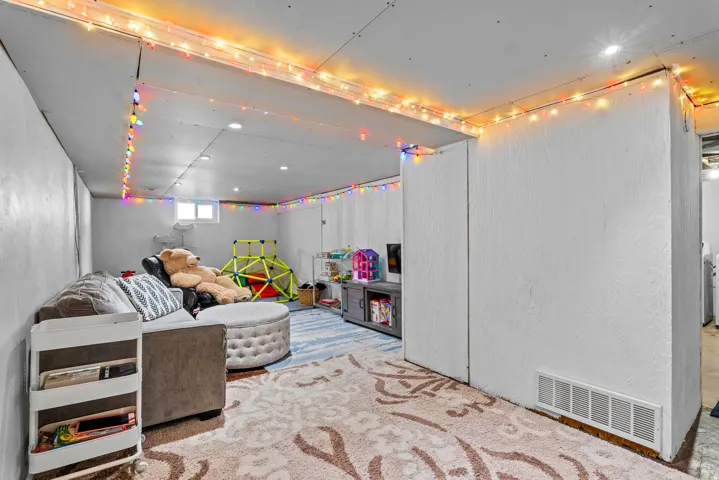 Finished basement space featuring recessed lighting, a window, and a painted concrete floor with an area rug