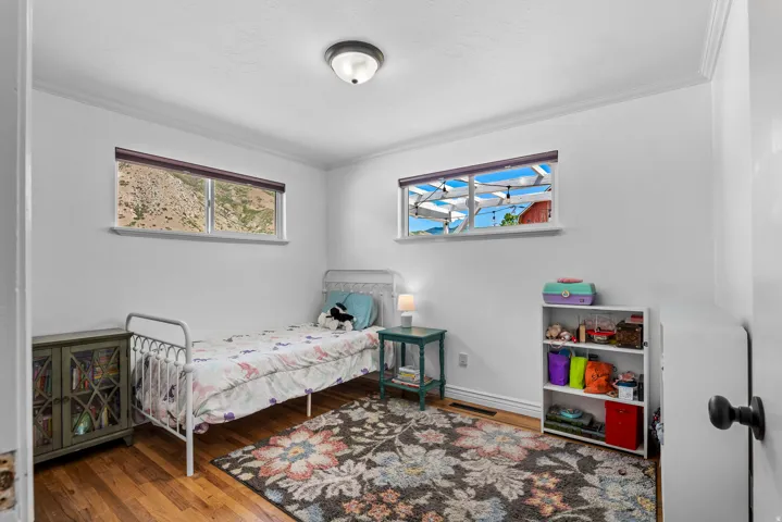 Bright room featuring wood-finish flooring, white walls, and crown molding