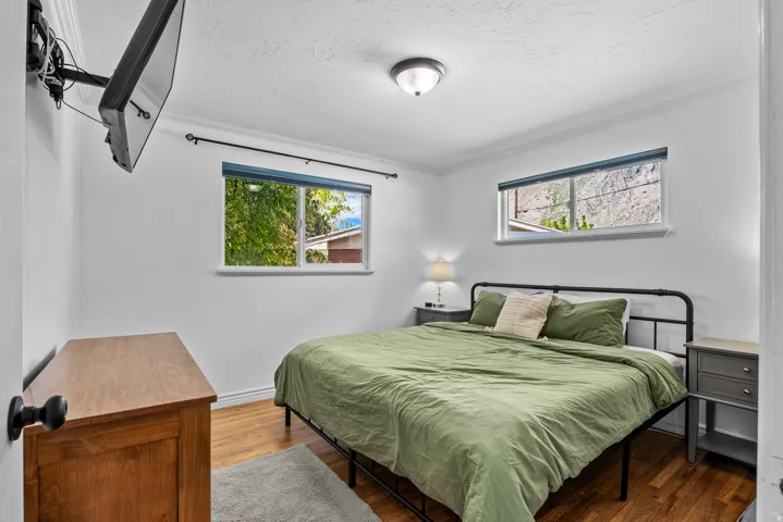 Well-lit interior featuring two windows, wood-finish flooring, white walls, and crown molding