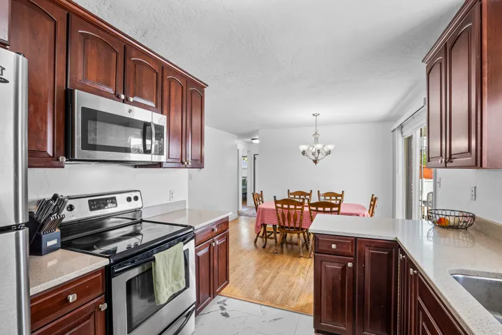 Kitchen with dark wood cabinetry, light-toned countertops, and stainless steel appliances