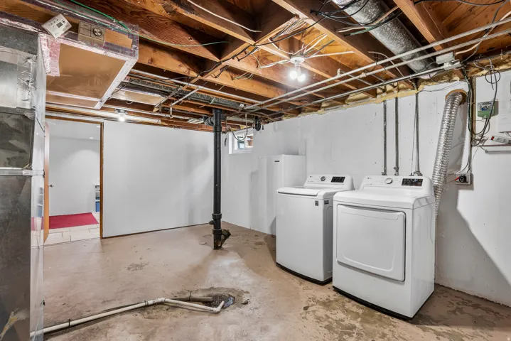 Laundry area featuring a top-loading washing machine and front-loading dryer, exposed wood joists, a support beam, painted concrete walls, and concrete flooring