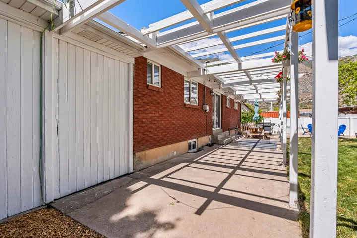 Extended concrete patio featuring a white pergola structure