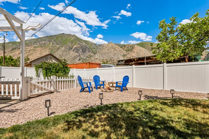Private backyard featuring a dedicated fire pit area, white picket fence, and full-height privacy fencing