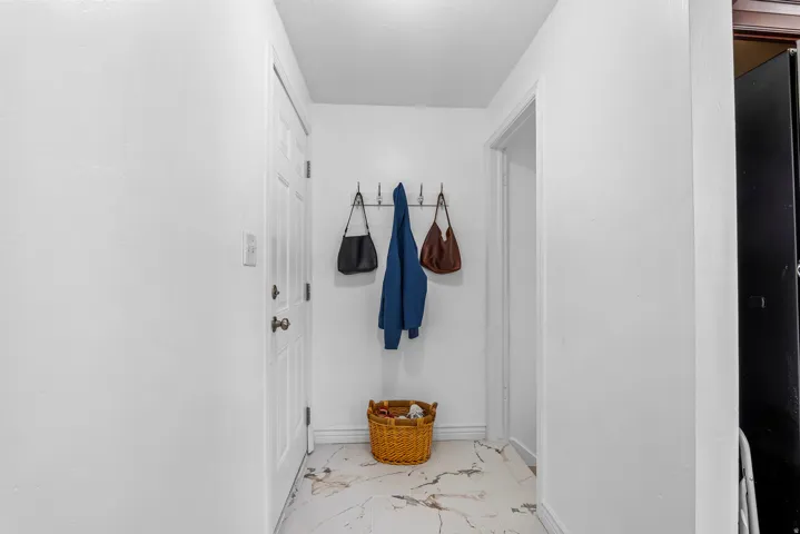 Entryway featuring white paneled door, patterned tile flooring, and white painted walls